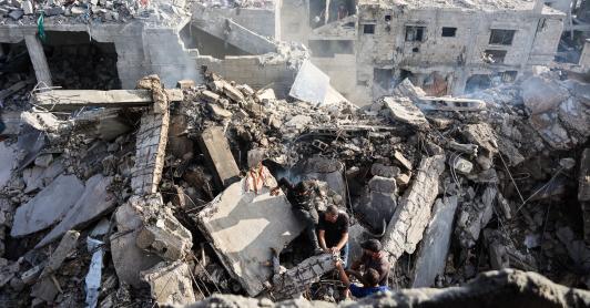 Palestinos intentan recuperar un cadáver de entre los escombros de una casa destruida en un ataque israelí durante la noche, en la ciudad de Gaza.