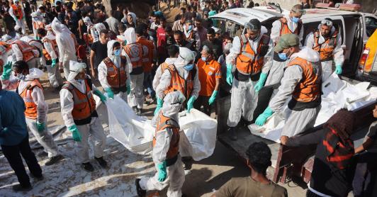 Miembros de Defensa Civil descargan bolsas con los restos mortales de los miembros de la familia Shahebar, que fueron enterrados en tumbas temporales, mientras son trasladados al cementerio Sheikh Shaaban, en la ciudad de Gaza, el 24 de octubre.