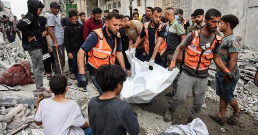 Palestinos transportan un cadáver que recuperaron de los escombros de una casa destruida en un ataque israelí perpetrado durante la noche en la ciudad de Gaza.