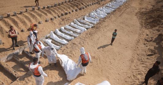 Trabajadores sanitarios y civiles realizan un entierro masivo de palestinos en un cementerio de Jan Yunis, en el sur de la Franja de Gaza.
