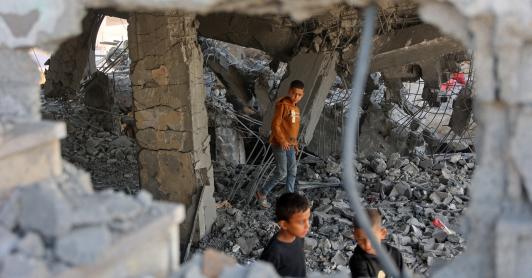Niños palestinos caminan entre los escombros de un edificio dañado perteneciente al Ministerio de Dotaciones Religiosas, que albergaba a personas desplazadas en el barrio de Zeitoun, en la ciudad de Gaza. 