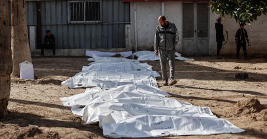 Un hombre observa las bolsas con restos humanos tras la exhumación de las tumbas por parte de la defensa civil en el interior del Hospital Bautista Árabe Al-Ahli para trasladar los restos a los cementerios oficiales de la ciudad de Gaza. 