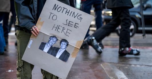 Un manifestante sostiene una pancarta con fotografías de Jeffrey Epstein (izquierda), un acaudalado financiero estadounidense que murió en prisión en 2019 mientras esperaba juicio por tráfico sexual de menores, y del presidente de Estados Unidos, Donald Trump (derecha), durante una manifestación contra el Foro Económico Mundial (FEM) en vísperas de la reunión anual del FEM en Davos.