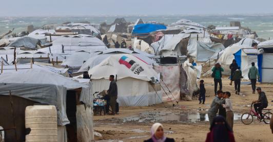 Los desplazados palestinos caminan cerca de tiendas de campaña y refugios improvisados mientras la región sufre las frías condiciones invernales en el campo de refugiados de Al-Mawasi, en el sur de la Franja de Gaza. 