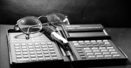 calculadora financiera antigua, gafas y lapicero