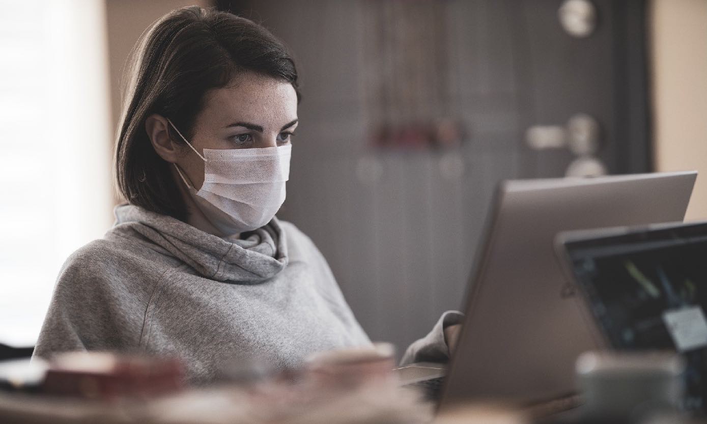 Mujer con tapabocas frente a un computador